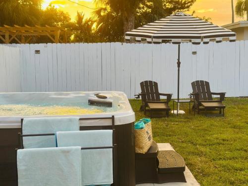 a hot tub in a yard with chairs and an umbrella at Wilton Manors Guesthouse in Fort Lauderdale