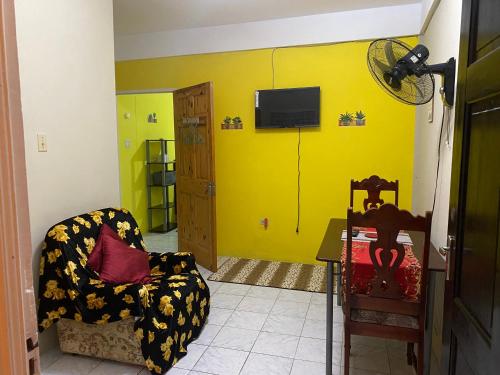 ein Wohnzimmer mit gelber Wand und Stuhl in der Unterkunft Cozy Oasis Hideaway in Port Antonio