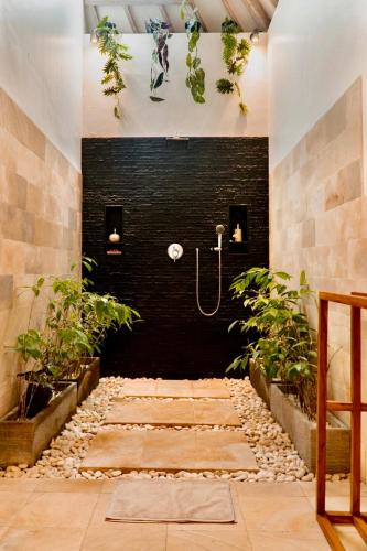a bathroom with a shower with plants in it at Villa Kayu in Gili Air