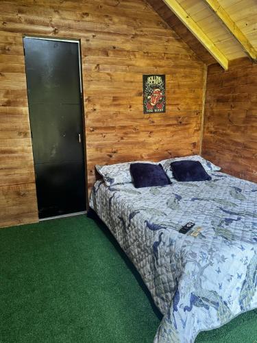 a bedroom with a bed in a wooden wall at Cabañas del bosque - La casa en la piedra in Choachí