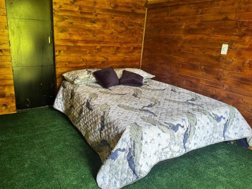 Un dormitorio con una cama en una pared de madera. en Cabañas del bosque, en Choachí