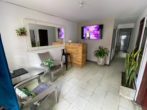 a living room with chairs and a counter with a tv at Bau 420 HOSTAL in Cali