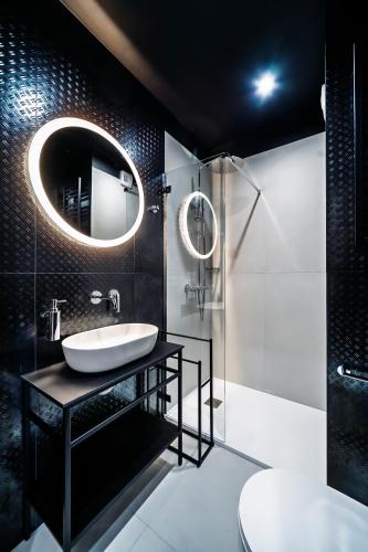 a black bathroom with a sink and a mirror at Apartament Parkya Slow by Warmia4Rent in Olsztyn