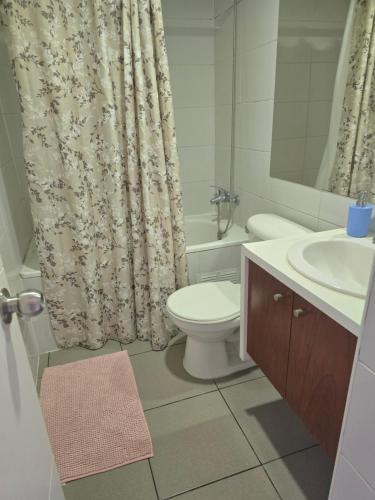 a bathroom with a toilet and a sink and a shower curtain at Departamento hermosa vista de la ciudad in Rancagua