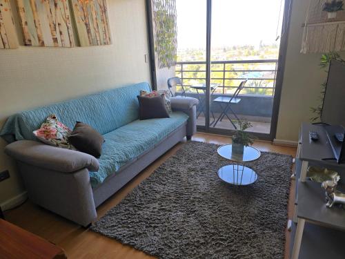 a living room with a blue couch and a balcony at Departamento hermosa vista de la ciudad in Rancagua