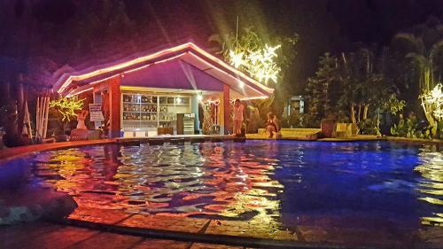 a swimming pool in front of a building at night at Deep Forest Garden Hotel in Puerto Princesa City