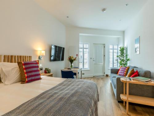 a bedroom with a large bed and a couch at Belgrave Sands Apartment in Torquay