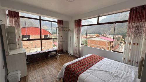 a bedroom with a bed and two large windows at Valle Sagrado in Coya