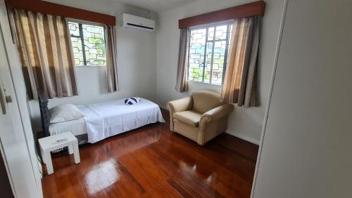 Un dormitorio con una cama y una silla y ventanas. en Loverly Three Bedroom Rental Pool Outdoor Area Upper, en Suva