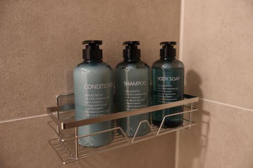 a rack with three bottles of soap and shampoo at VINoKAT Winestyle Living - Südliche Weinstraße in Kirrweiler