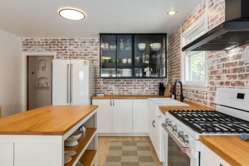 a kitchen with white cabinets and a brick wall at Ramsay Retreat Spa Vibes Hot Tub & Skyline Views in Calgary