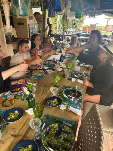 a group of people sitting around a table eating food at JaParaíso Pousada Ateliê in Japaratinga