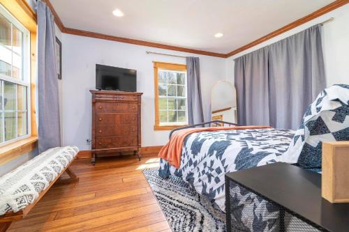 a bedroom with a bed and a tv and a couch at Remodeled 1920s Charmer Near ETSU, JCMC & Downtown in Johnson City