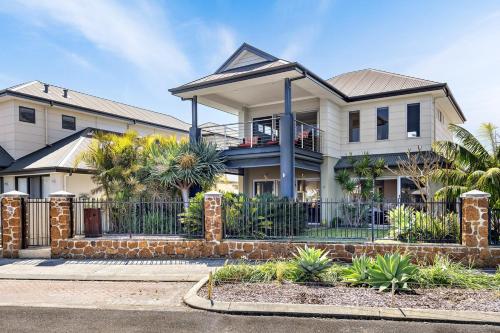 a house with a fence and palm trees at Two-Storey Lakeview Retreat at Dunsborough Lakes in Dunsborough