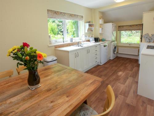 Una cocina con una mesa de madera con un jarrón de flores encima. en Netherwood, en Bakewell