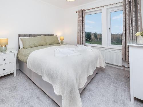 a white bedroom with a bed and a window at Sealladh Na Mara in Pollachar