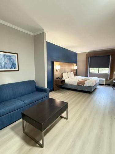 ein Wohnzimmer mit einer blauen Couch und einem Bett in der Unterkunft Comfort Inn & Suites Tyler - Lindale in Tyler