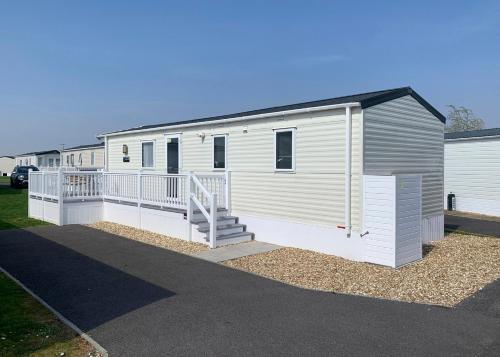 a mobile home with a porch and stairs on it at Riverside Holiday Village in Uphill