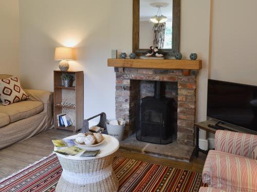 a living room with a fireplace and a couch at The Garden Cottage in Rudston