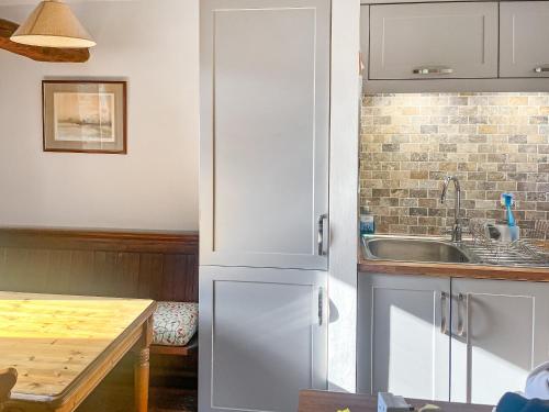 a kitchen with a white refrigerator and a sink at Blacksmiths Cottage in Gillamoor
