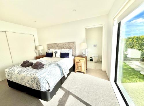 a bedroom with a bed and a large window at Deluxe Downtown Mount Maunganui in Mount Maunganui