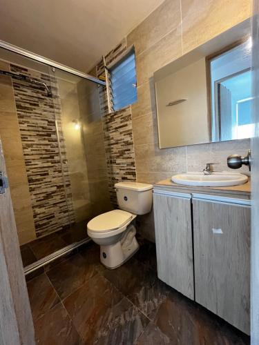 Un baño con inodoro, lavabo y espejo. en Amanecer llanero, en Villavicencio