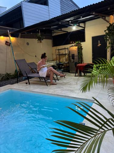a woman sitting in a chair next to a swimming pool at Casa Pelíkano Uvita in Uvita