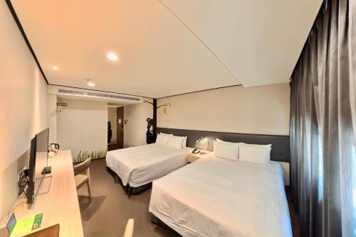 a hotel room with two beds and a desk at Energy Inn in Taipei