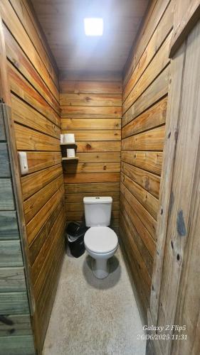 a bathroom with a toilet in a wooden wall at Chalés Surfside Maresias in Maresias