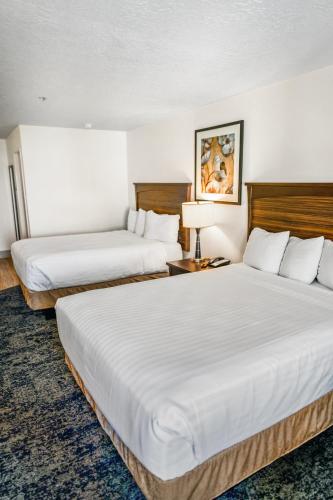 two beds in a hotel room with white sheets at Crystal Inn Hotel & Suites - Salt Lake City in Salt Lake City