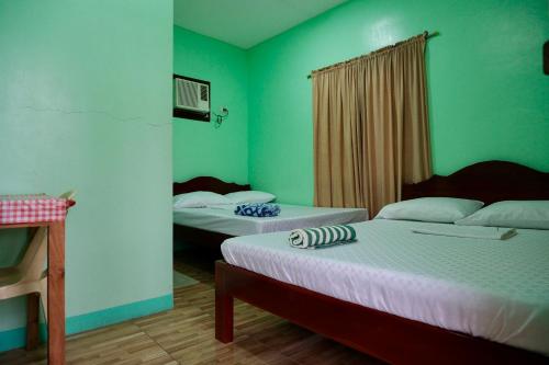 two beds in a room with green walls at Sangi Tourist Inn near Kawasan Badian Canyoneering in Alegria