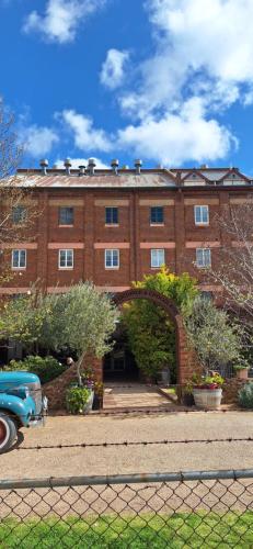 an old car parked in front of a brick building at Aeris Country Cottage in Junee