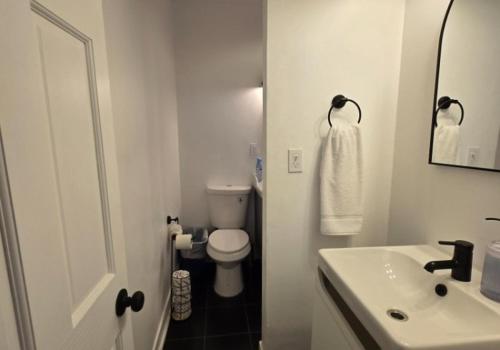 a white bathroom with a toilet and a sink at Grand House in Chicago