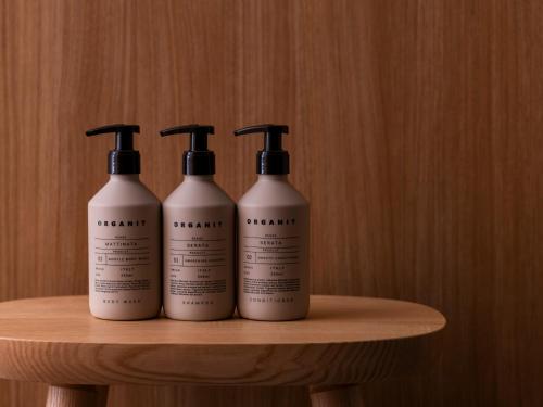 three bottles of shampoo sitting on a wooden shelf at Mitsui Garden Hotel Kyoto Sanjo PREMIER in Kyoto