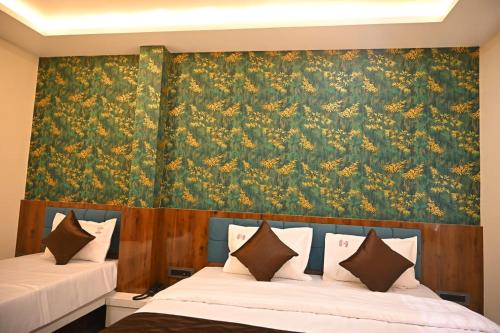 a bedroom with two beds with a floral wallpaper at Hotel Diamond Palace in Bhopal