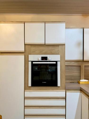 eine Küche mit weißen Schränken und einem Fernseher in der Unterkunft Casa Serein in Fare