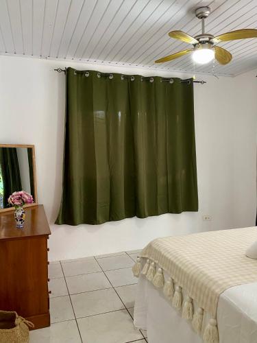 ein Schlafzimmer mit einem grünen Vorhang und einem Bett in der Unterkunft Casa Serein in Fare