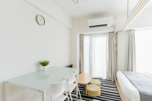 a white room with a bed and a table and chairs at Yakuin apartment in Fukuoka