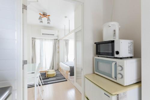a kitchen with a microwave on a counter with a room at Yakuin apartment in Fukuoka