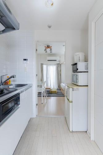 a white kitchen with a sink and a refrigerator at Yakuin apartment in Fukuoka
