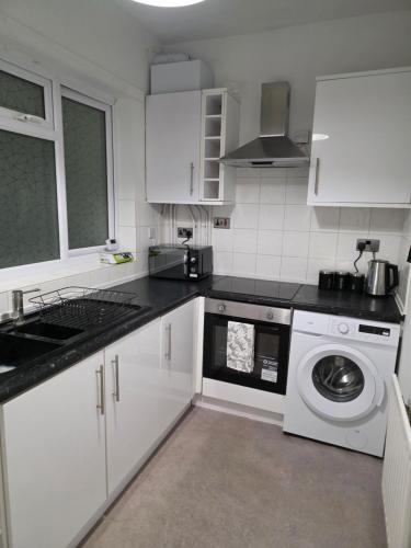 a kitchen with white cabinets and a washing machine at Cozy one bedroom flat in Chatham
