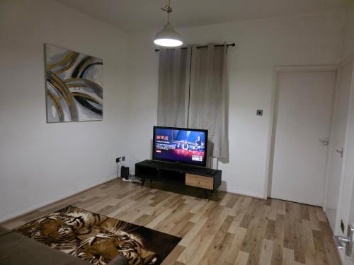 a living room with a flat screen tv on a wooden floor at Cozy one bedroom flat in Chatham