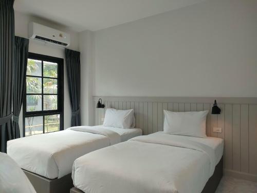 two beds in a hotel room with a window at The Target Hotel chaingrai in Chiang Rai