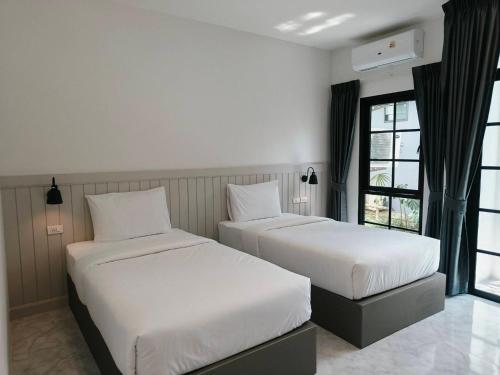 a bedroom with two beds and a window at The Target Hotel chaingrai in Chiang Rai