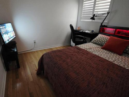 a bedroom with a bed and a desk and a television at Semi-Private Townhouse - 3 Bedrooms - 4 beds - Free Parking, Wifi, Netflix in Toronto