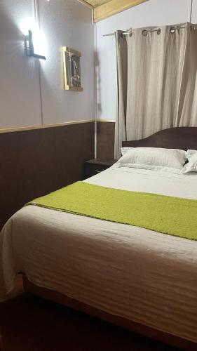 een slaapkamer met een groot bed en een groene deken bij Cabañas Cordillera in Puerto Cisnes