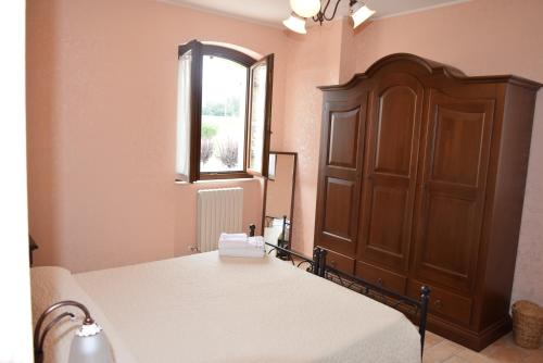 a bedroom with a bed and a wooden cabinet at Postiglione Country House in Cingoli