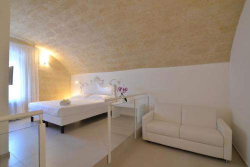 a bedroom with a bed and a couch and a chair at Casa Blanca Matera in Matera