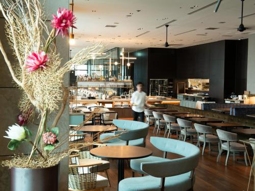 a man standing in a restaurant with tables and chairs at Mitsui Garden Hotel Ginza Premier in Tokyo