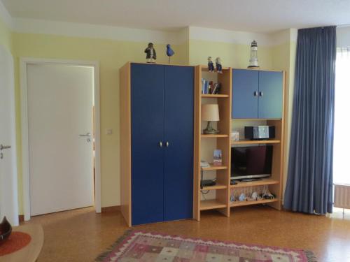 a living room with a blue cabinet and a tv at Strandläufer im Haus Strelasund in Binz